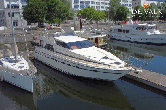 Luxueuze motorboot aangemeerd in een haven met andere boten op de achtergrond.